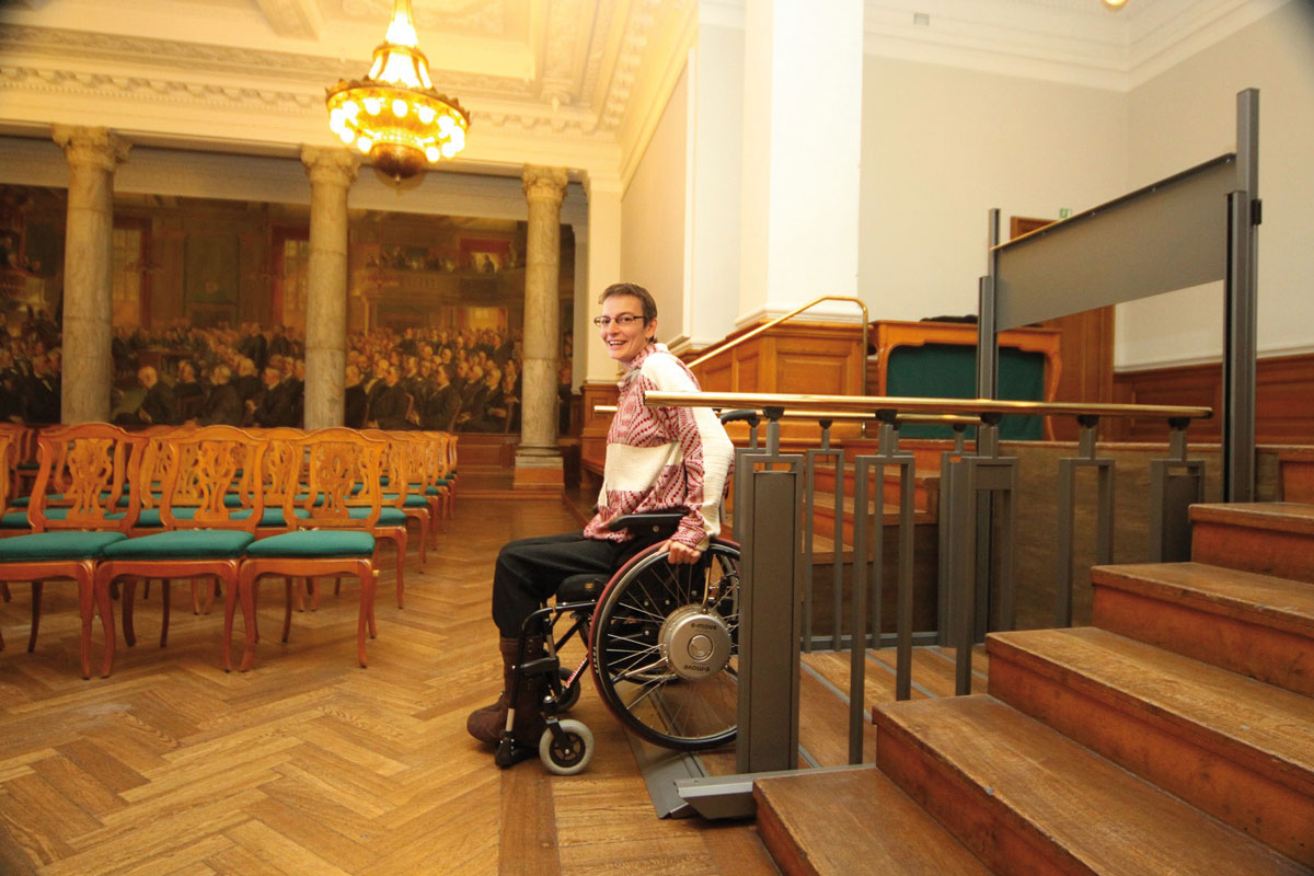 lift-statt-treppe-flexstep Rollstuhlfahrerin nutzt die Liftfunktion der FlexStep-Treppe in öffentlichem Gebäude