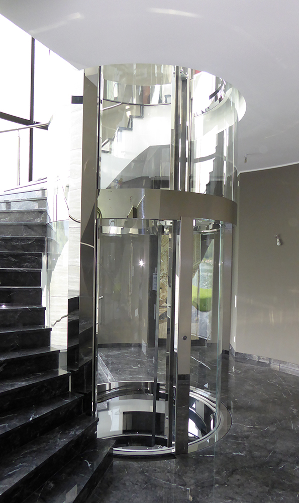 runder-glasaufzug a building with glass walls and a rock